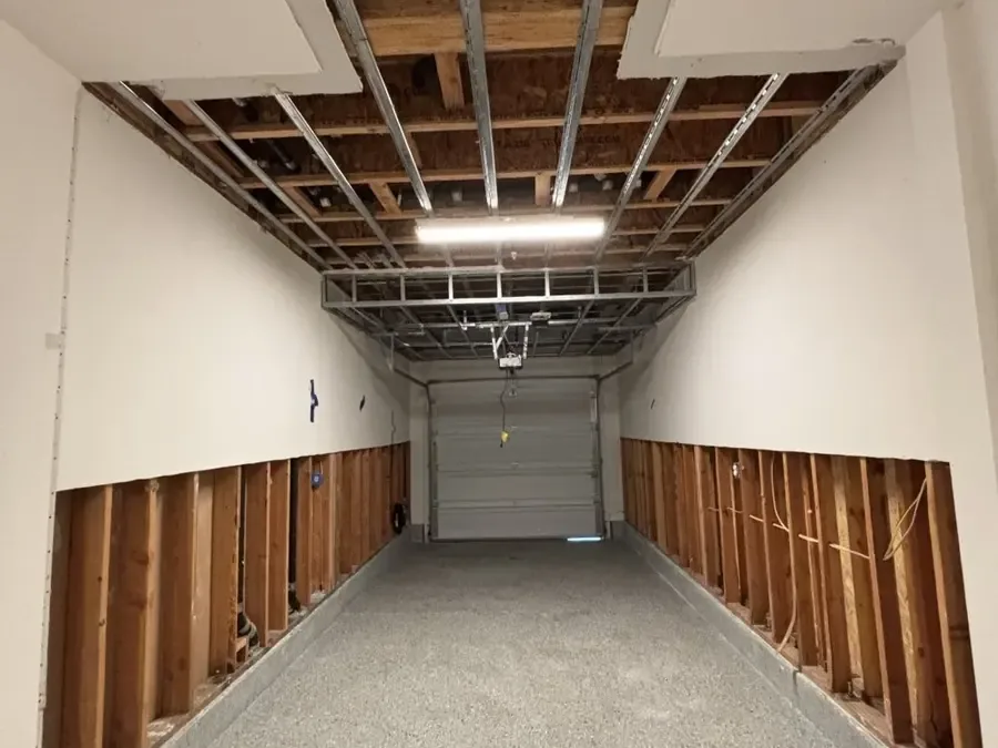 Garage drywall cut away at the base of the wall after a water heater leaked