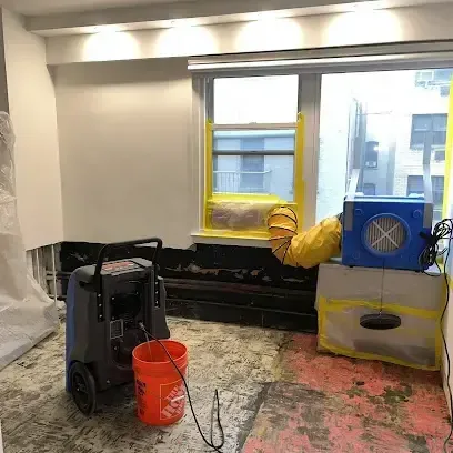 A dehumidifier and an air mover running together in a room where the flooring has been pulled up