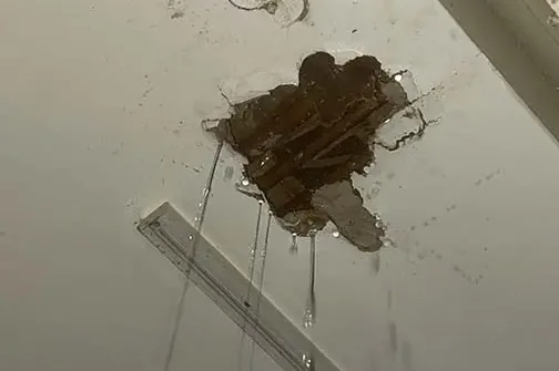 Water dripping through a ceiling below a leaking roof
