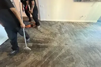 Two restoration technicians pulling water from a soaked floor with an extraction wand